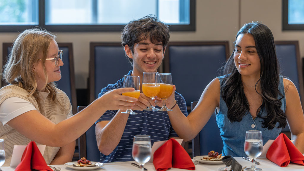 Three Charlotte Cross-Country athletes make a toast.