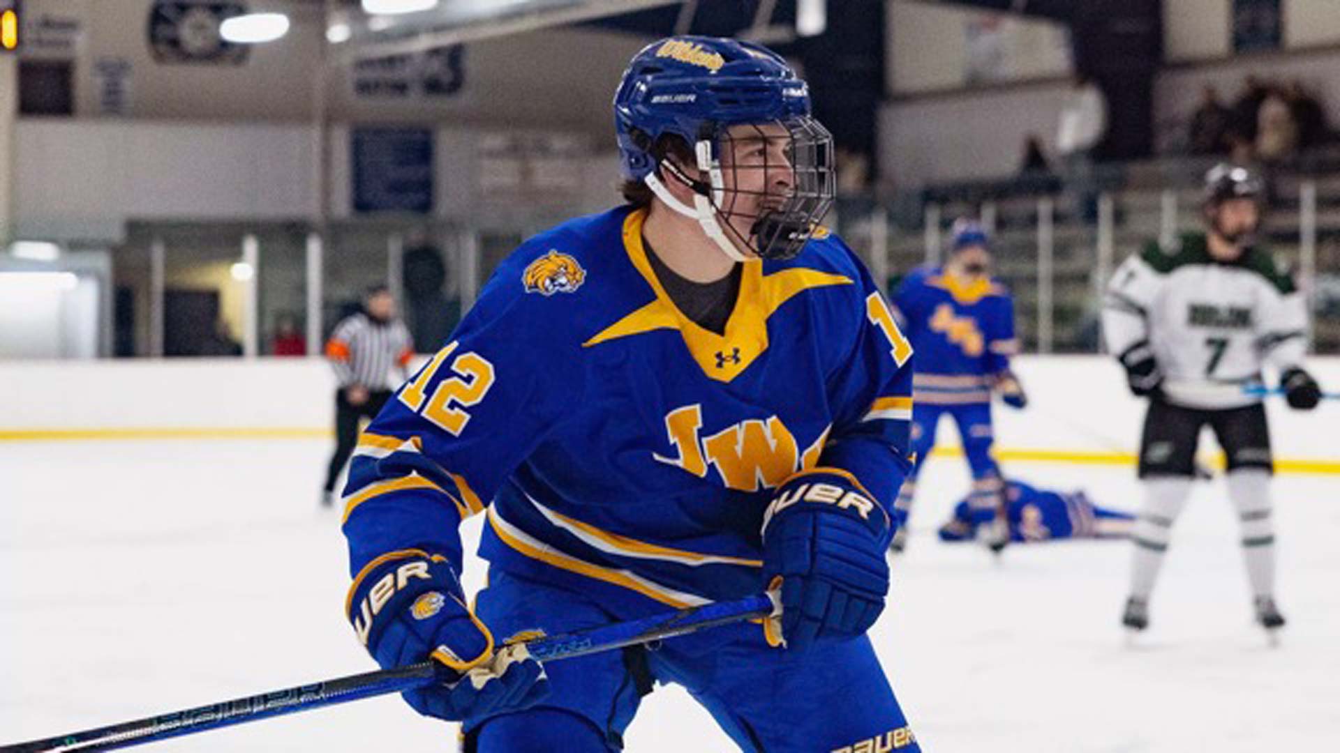 Davis on the ice in blue and yellow uniform holding hockey stick