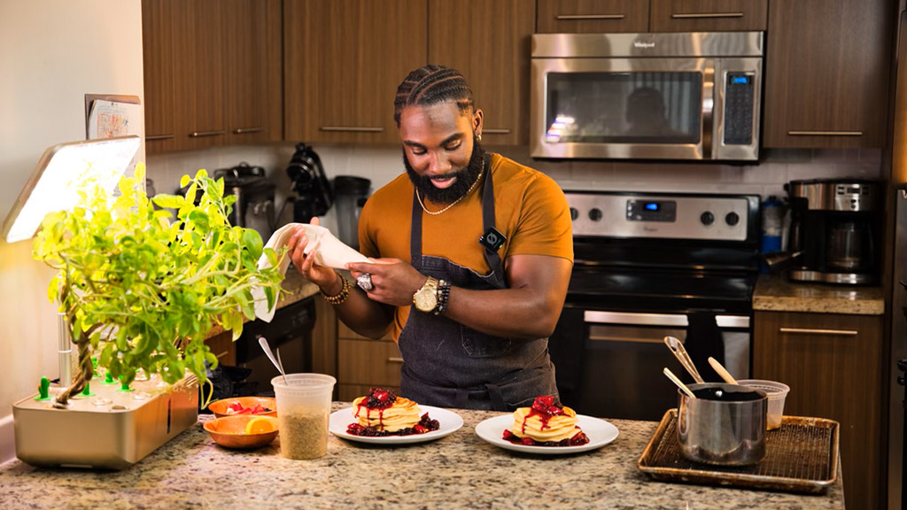 Nol Foretia '16 prepares plates of food in a kitchen