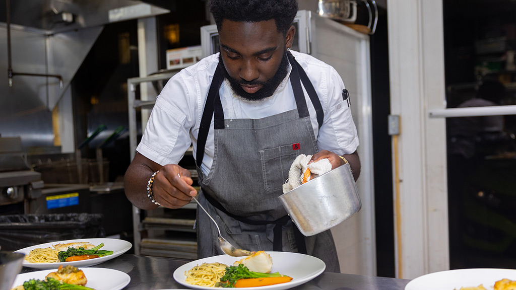Chef Nol Foretia '16 prepares meals of fish, pasta and veggies