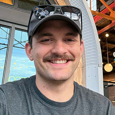 Headshot of Zacheriah Rau '29 smiling while outside of a building
