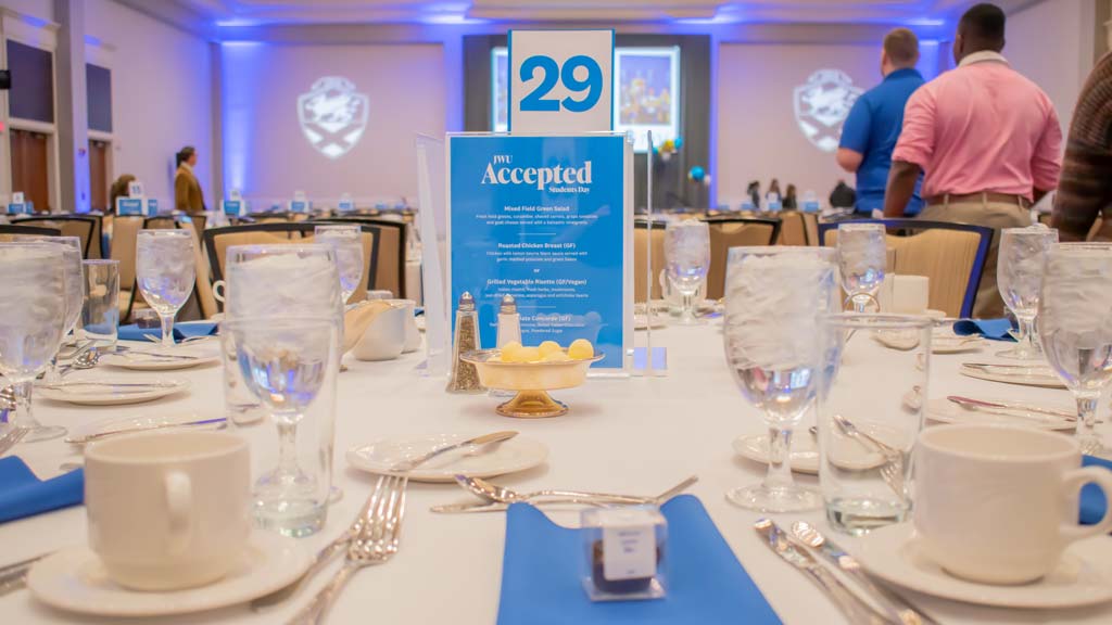 A table with plates and silverware, and a centerpiece saying JWU Accepted Students Day