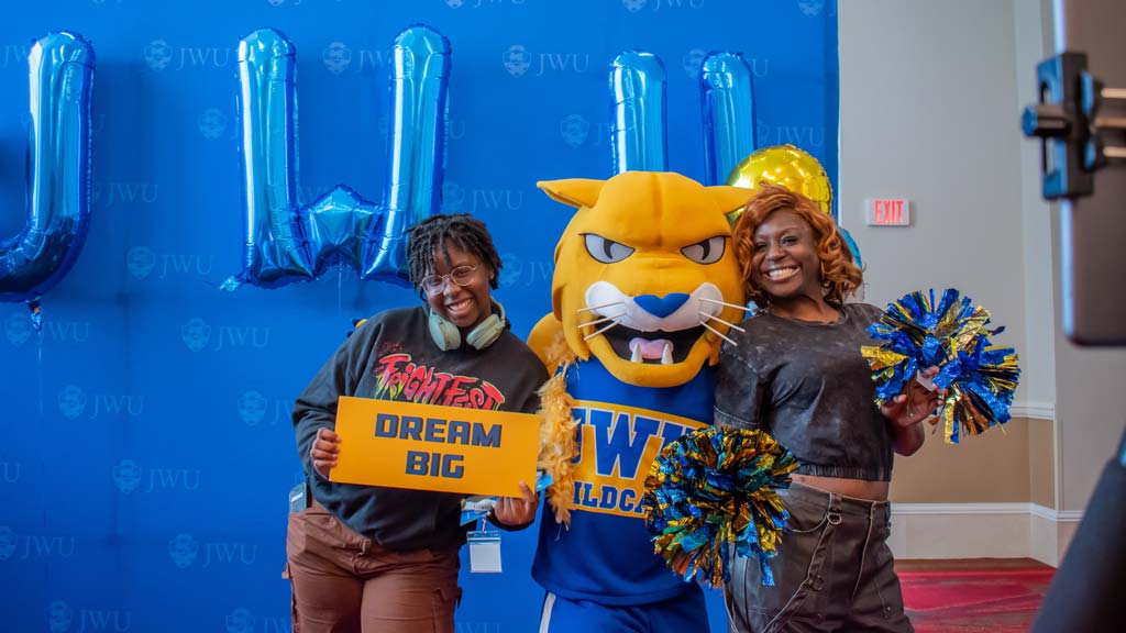 A student with their parent posing with Wildcat Willie
