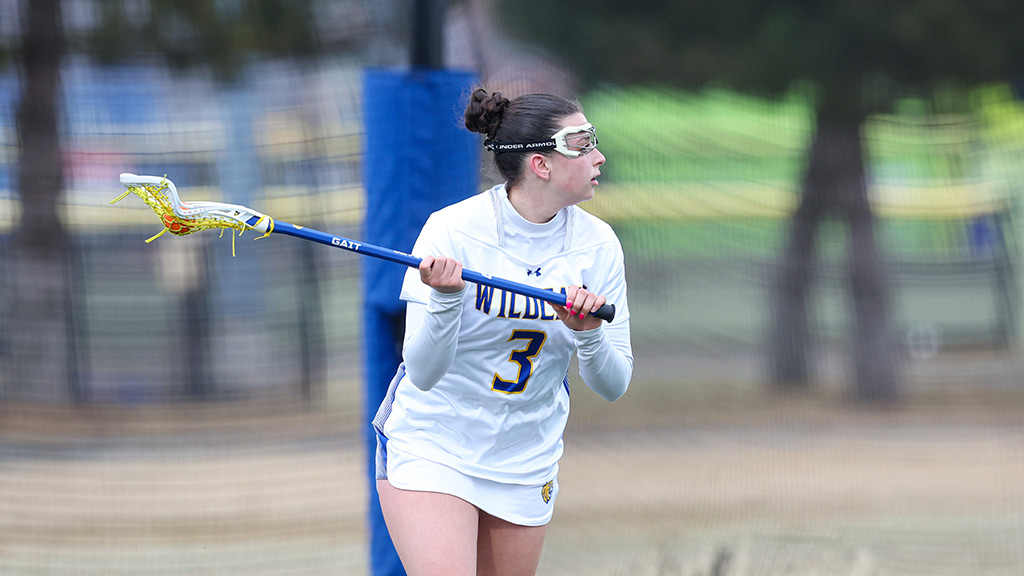 Mila running under her teammates lacrosse sticks smiling