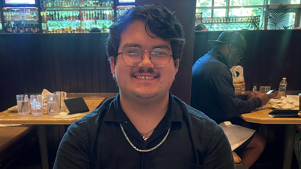 photo of a young man in glasses, Amren Hartleigh '26, smiling
