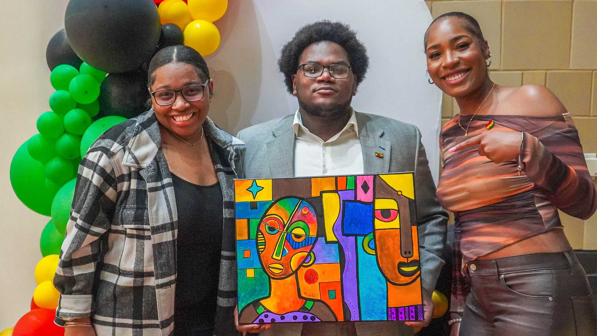 Students pose with artwork at a celebration