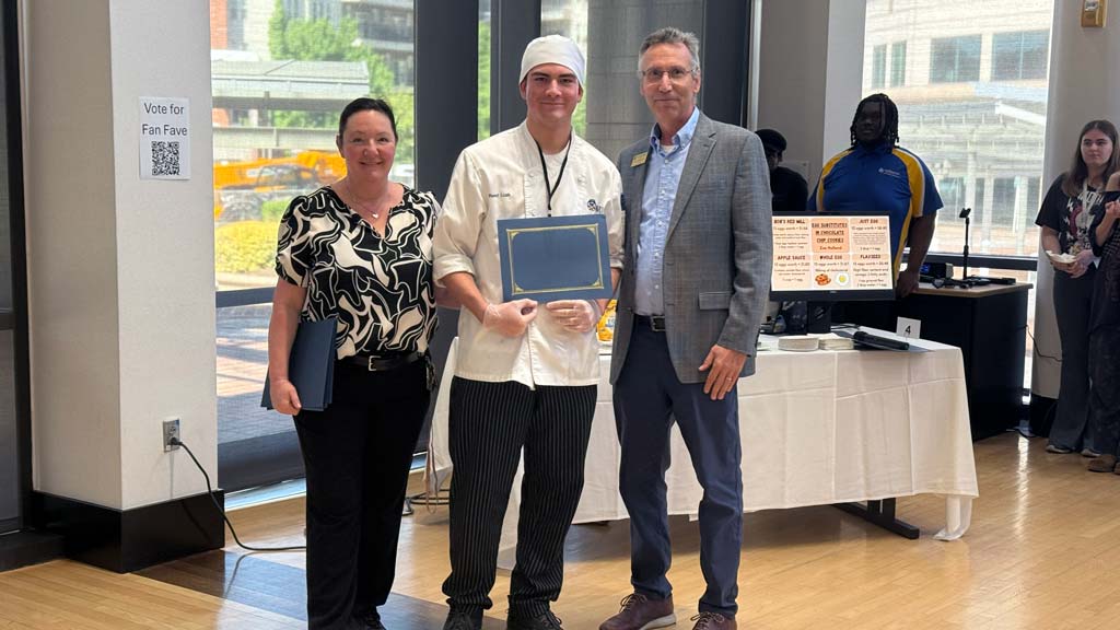 One of the seven students, Reed Lusk, who won at Charlotte's Symposium, posing with their award