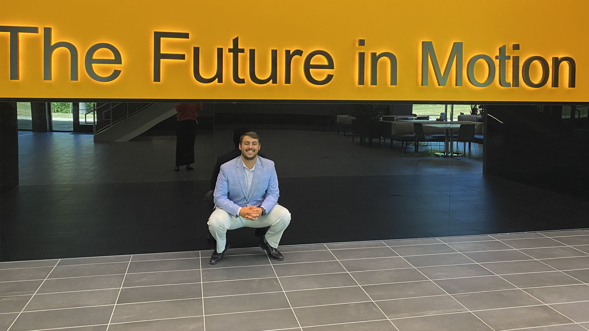 John Billinis ’26 in front of a sign reading, “The future in motion.”