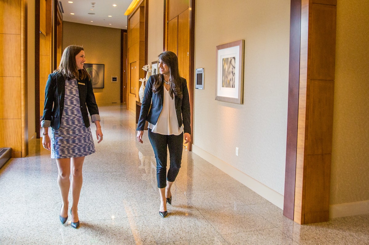 Two professional females walking in the hallway of a hotel