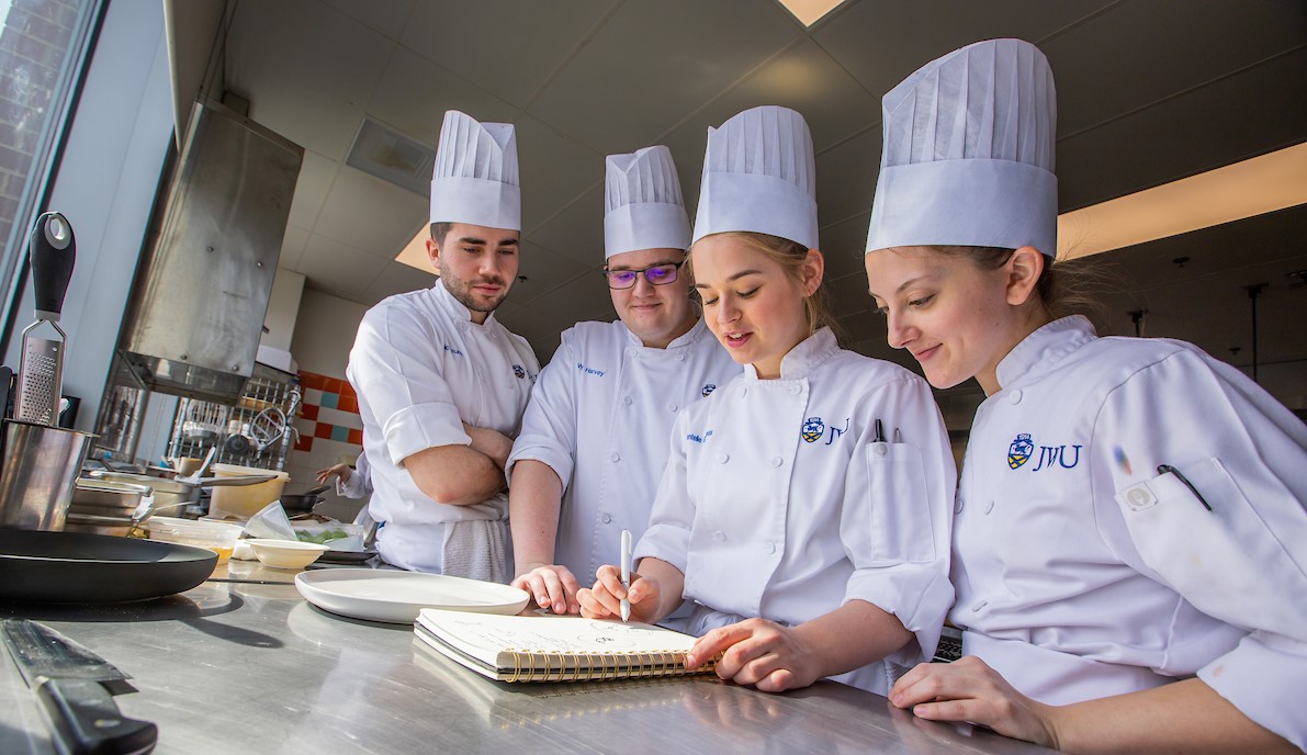 Culinary students work together at a desk